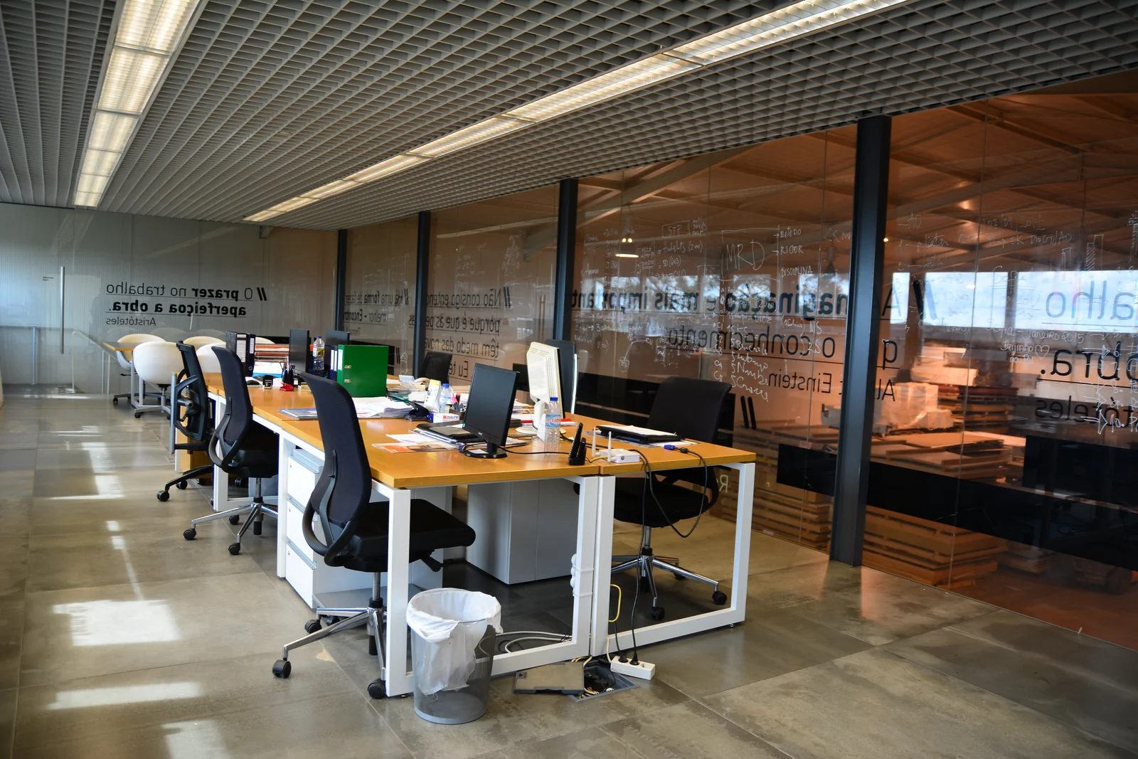 Espaço de trabalho com mesas, computadores e divisórias envidraçadas